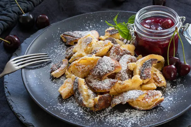 Small pancakes on a black plate with berries and decoration