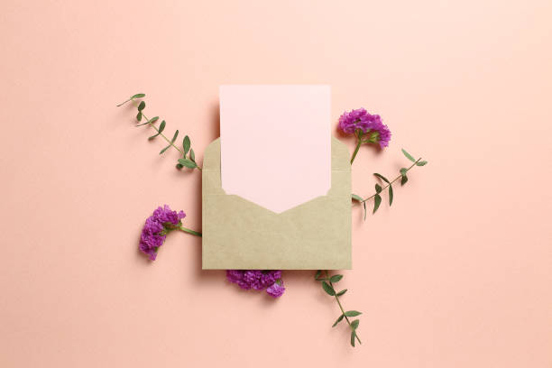 Kraft envelope and empty card with statice flower, eucalyptus leaves on pink background. Floral composition, flat lay, top view, copy space