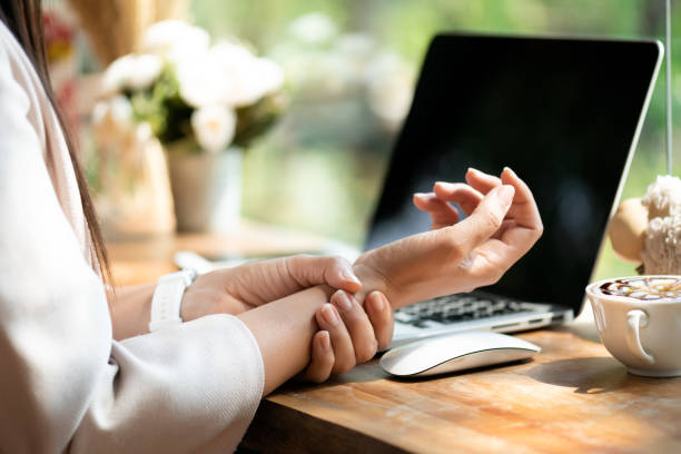 mujer de primer plano sosteniendo su dolor de muñeca de usar la computadora. dolor de manos con síndrome de oficina por enfermedad ocupacional. - pain joint human hand arthritis fotografías e imágenes de stock