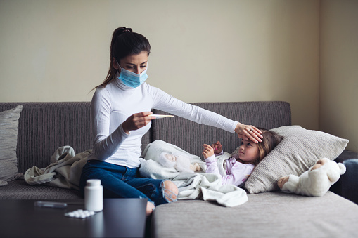 Una madre mide la temperatura de su hijo enfermo en casa. photo