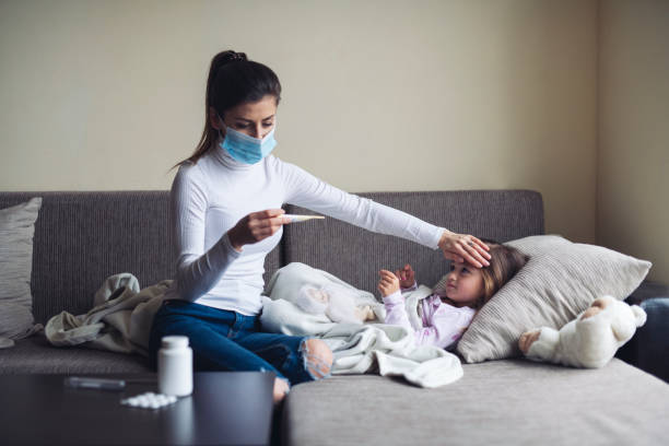 A Mother Measure Temperature On Her Sick Child At Home. Mother wearing face protection mask at home and measure a temperature on her sick child. medical condition stock pictures, royalty-free photos & images
