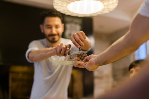 istock Man dishing up meat for partner at the barbecue dinner table 1208305273
