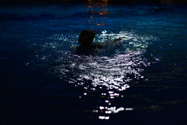 The boy drowns at night in the hotel pool The boy drowns at night in the hotel pool. kids swimming at night stock pictures, royalty-free photos & images