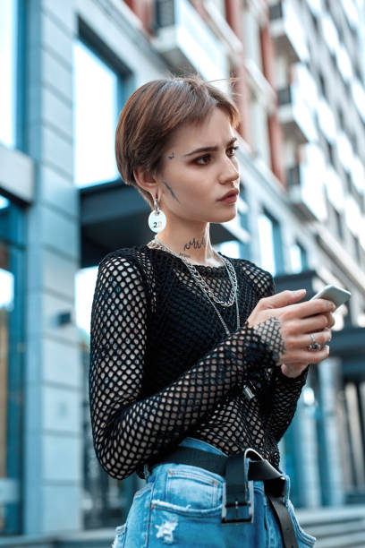 istock Urban Style. Young stylish woman standing outdoors using app on phone pensive 1208306995