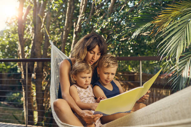 Story time Shot of a young mother hanging outside with her son and daughter hammock relaxation women front or back yard stock pictures, royalty-free photos & images