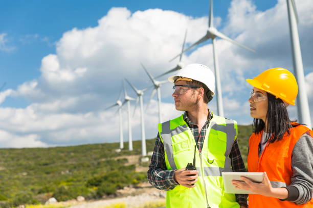 istock Young workers looking and checking wind turbines at field 1208308629