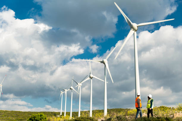 Young engineers looking and checking wind turbines at field