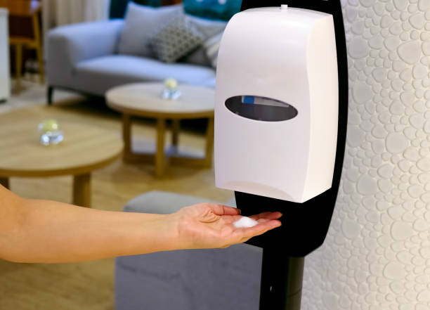 Closeup of Hands under the automatic alcohol dispenser. stock photo