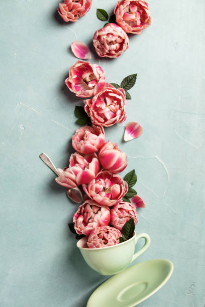 istock Creative layout made of coffee or tea cup with pink flowers on blue background 1208311932