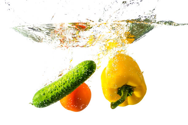 istock Peppers, tomato and cucumber fall into the water with splashes, isolated on a white background. 1208312960