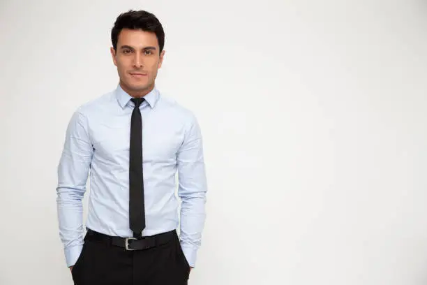 Photo of Young businessman standing with hands in pocket isolated over white background