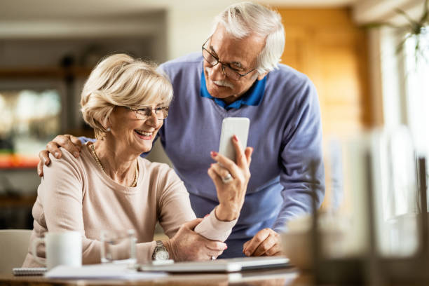 istock Happy senior woman using cell phone with her husband at home. 1208314519