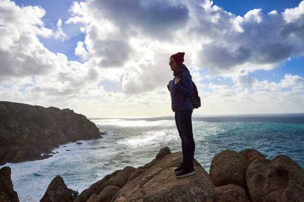 young woman tourist at cape cabo da roca standing on the rocky edge of the cliff. the waves of the ocean break on the rocks at the bottom of the cliff - hiking coastline waters edge sunny imagens e fotografias de stock