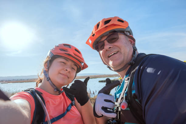 istock Father and Daughter Cyclists Posing for Selfie at Shoreline Lake 1208315021
