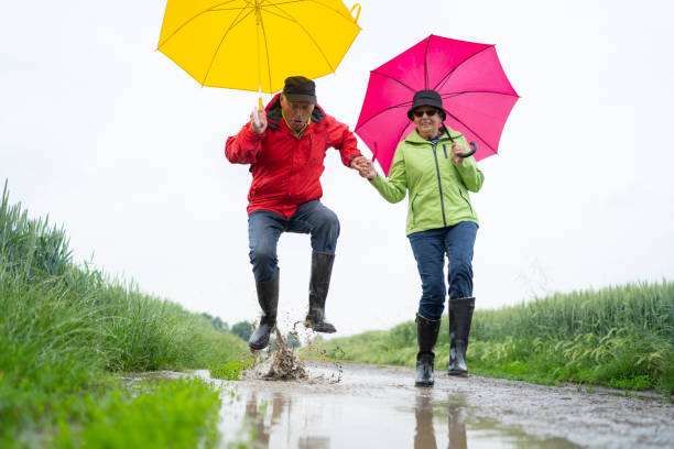 senior couple having fun on rainy day walk - senior adult cheerful adventure discovery imagens e fotografias de stock