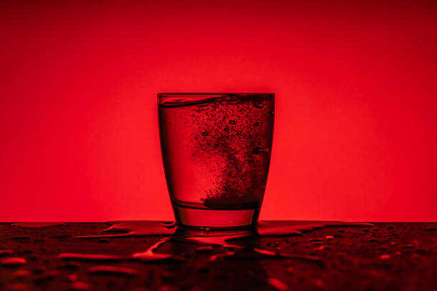 istock Effervescent tablet dissolving into glass of water - red  background 1208315238