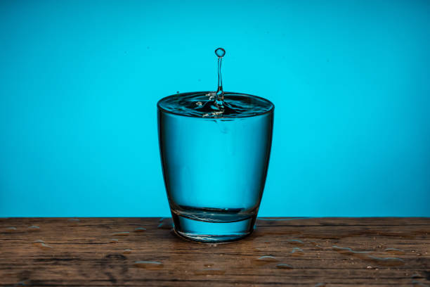 istock Raindrops fall in glass full with water - blue background 1208315970
