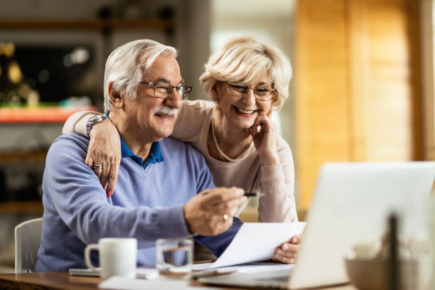 счастливая зрелая пара с помощью ноутбука при планировании своего домашнего бюджета. - retirement senior adult finance couple стоковые фото и изображения