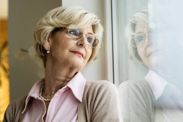 istock Mature woman day dreaming while looking through the window. 1208317143