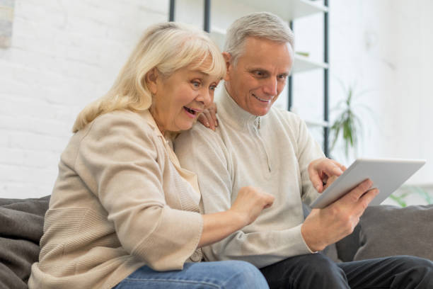 istock Happy elderly couple using gadget in living room 1208318474