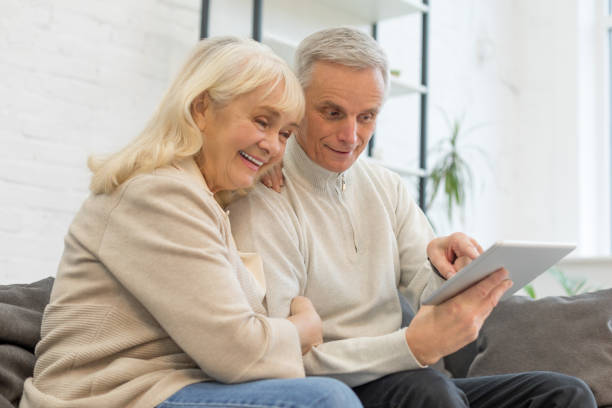 istock Happy elderly couple using gadget in living room 1208320406