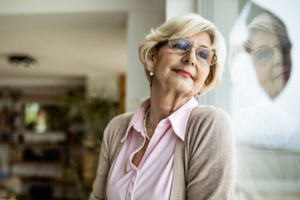 istock Pensive mature woman looking through the window. 1208320543