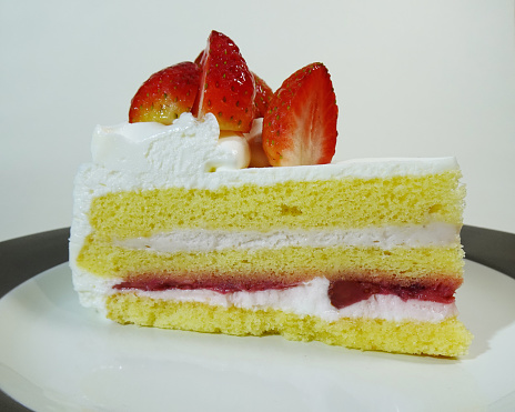 Strawberry shortcake consists of vanilla sponge cake, cheese cream and fresh strawberry in a round brown and white plate