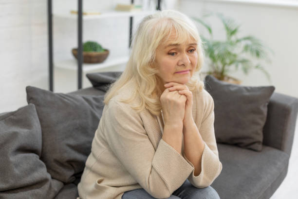 istock Distressed elderly lady sitting on sofa at home 1208320909