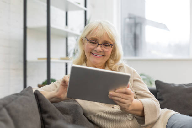 istock Pretty older woman looking at gadget screen at home 1208322016
