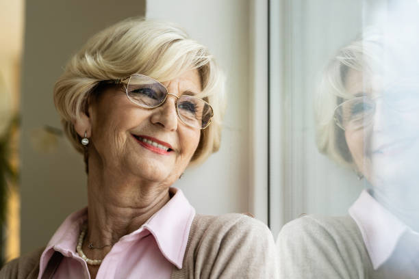 istock Smiling pensive senior woman relaxing by the window. 1208322826