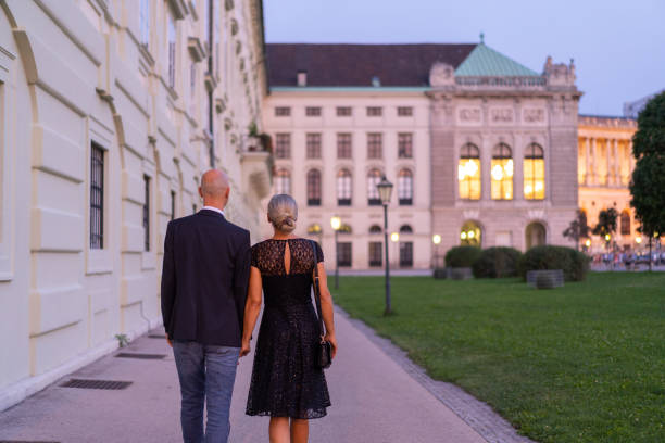 following couple in historical city center of vienna on summer evening rear view of adult couple walking together hand in hand through historical center of vienna on summer evening on their way to dinner party in city, shallow focus, background blurred, place for text unusual couple stock pictures, royalty-free photos & images