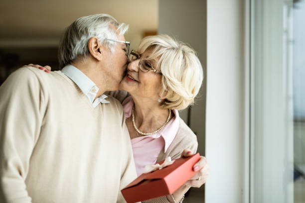 istock Happy senior woman surprising her husband with a gift. 1208324232