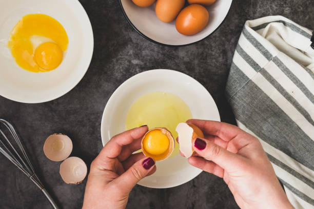 istock Cooking omlette. Woman's hands cookingomlette, breaking an fresh egg. Dark background. Food flat lay. 1208326468