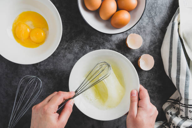 istock Cooking omlette. Woman's hands cookingomlette, breaking an fresh egg. Dark background. Food flat lay. 1208326481
