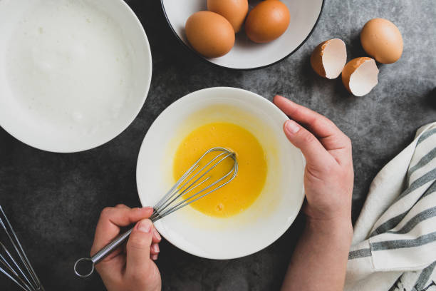 istock Woman's hands whisk eggs in bow. Cooking omlette for breakfast. Top view, flat lay of cooking process. Dark background. 1208326507