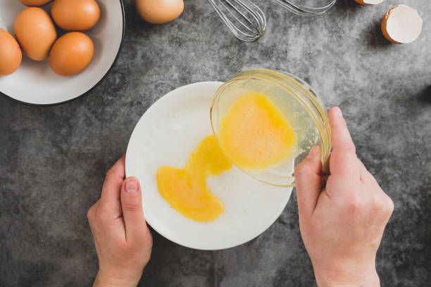 istock Cooking omlette. Woman's hands cookingomlette, breaking an fresh egg. Dark background. Food flat lay. 1208326551