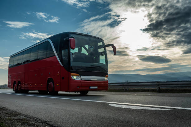 istock Red Modern tourist bus driving through highway on bright sunny sunset 1208326625