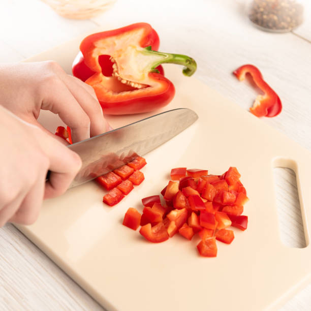 A section of bell pepper with a sharp knife on a cutting board made of artificial stone