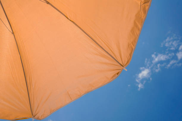 orange umbrella on blue sky with clouds. Happy holiday vacation concept