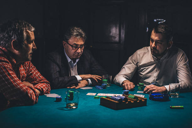 istock Men playing poker in dark room at night 1208332577