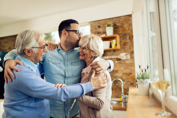 istock Affectionate man embracing his senior parents while greeting them in the kitchen. 1208333880