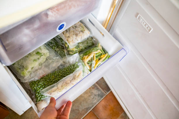 young man opening freezer with frozen vegetables inside - people cold frozen unrecognizable person imagens e fotografias de stock
