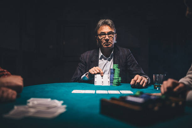 istock Senior man playing poker in dark room at night 1208337668