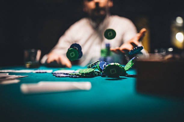 Man throwing gambling chips on table One man, gentlemen playing poker in dark room at night, throwing gambling chips on table. texas hold em photos stock pictures, royalty-free photos & images