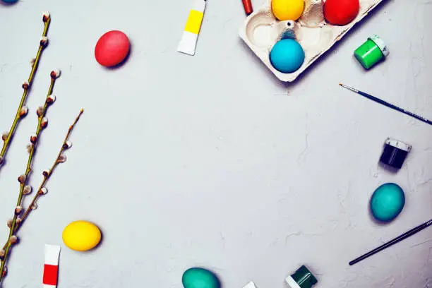 Happy easter. Colored eggs on gray concrete. Flowering, fur-seal willow, on an abstract gray background. Multicolored paints, brushes, watercolor. Space for text, empty space, flat lay.