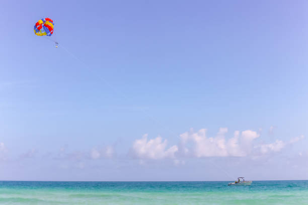 istock Single colourful paraglider behind a boat on a deserted blue ocean 1208339430
