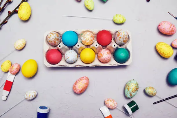 Happy easter. Colored eggs on gray concrete. Flowering, fur-seal willow, on an abstract gray background. Multicolored paints, brushes, watercolor. Real eggs and fake