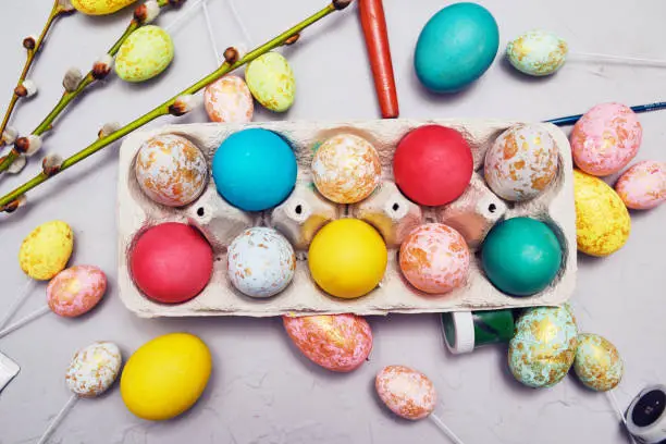 Happy easter. Colored eggs on gray concrete. Flowering, fur-seal willow, on an abstract gray background. Multicolored paints, brushes, watercolor. Real eggs and fake