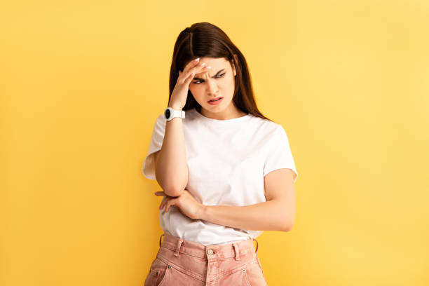 istock tired, upset girl touching head while suffering from headache isolated on yellow 1208340336