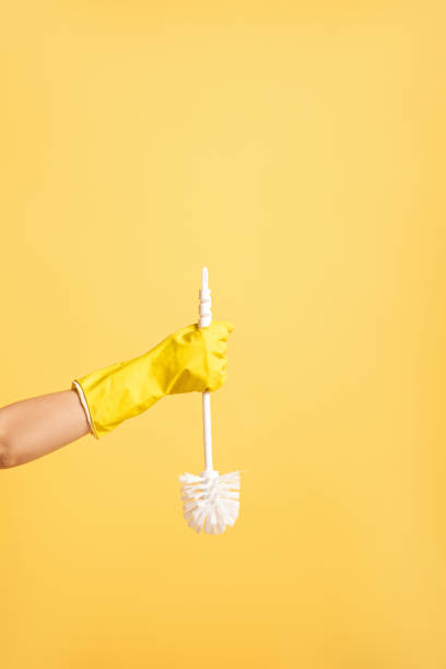 partial view of woman in rubber glove holding toilet brush isolated on yellow partial view of woman in rubber glove holding toilet brush isolated on yellow toilet brush stock pictures, royalty-free photos & images